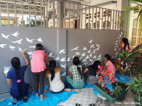 Colleagues and beneficiaries of Eden Ministry pain the wall of the centre together